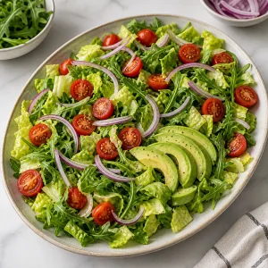 Salatbasis mit Romanasalat, Rucola, Tomaten, roter Zwiebel und Avocado