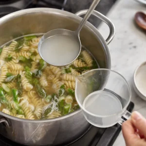 Starchy pasta water being scooped from the pot