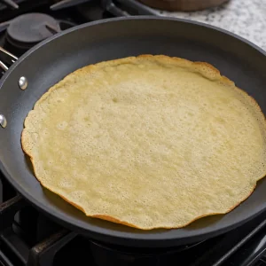 Thin Dutch pancake cooking until the top looks dry and edges turn golden