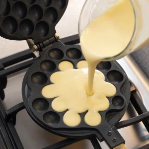 Bubble waffle batter poured into the center of the honeycomb iron.
