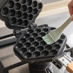 Bubble waffle iron brushed with oil and preheated for cooking.