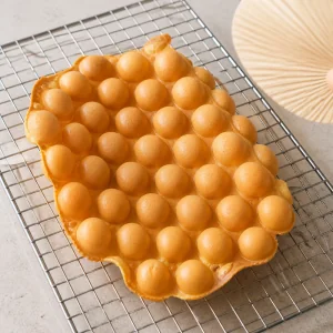 Fresh bubble waffle cooling on a wire rack to make the outside extra crispy.