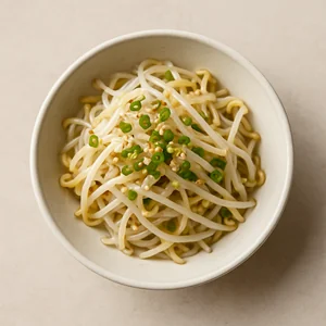 Finished mung bean sprout salad is served in a small bowl with sesame seeds and green onion.