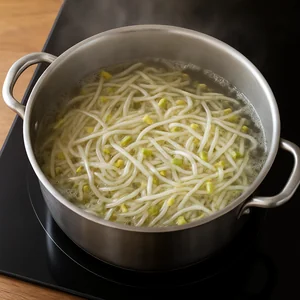Mung bean sprouts blanch in boiling water, looking slightly translucent.