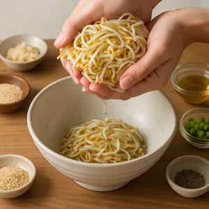 Wet sprouts are gently squeezed, with water dripping away into a bowl.