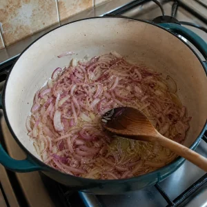 Thinly sliced red onion sauteing in oil in a heavy pot