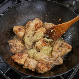 Ginger and garlic paste stirred into browned chicken pieces.