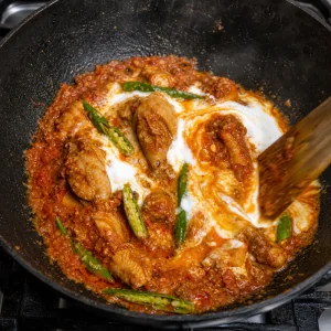 Yogurt and green chilies stirred into thickening chicken karahi sauce.