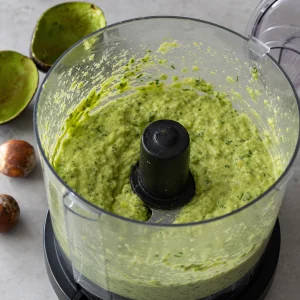 Creamy avocado tomatillo salsa in a food processor