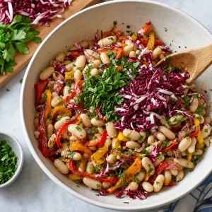 Petersilie und Radicchio werden unter den Bohnen-Paprika-Salat gehoben