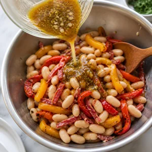 Vinaigrette wird über Bohnen und geröstete Paprikastreifen gegossen