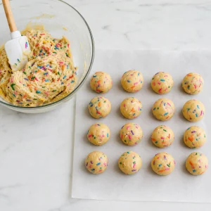 Funfetti-Teig und sechzehn gleichmäßig gerollte Teigkugeln