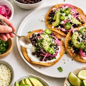 Black bean tostadas assembled with sour cream pickled onions jalapenos avocado queso fresco and cilantro