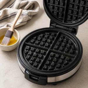 Empty waffle iron preheating on a bright kitchen counter.