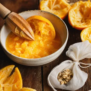 Squeezed orange flesh in a bowl with seeds tied in cheesecloth