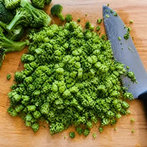 Blanched broccoli chopped into small pieces on a cutting board