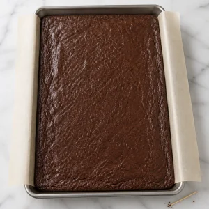 Thin baked brownie sheet in a parchment-lined pan