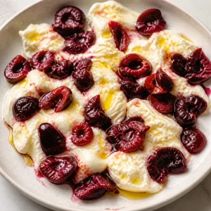 Olive oil drizzled over burrata and cherries