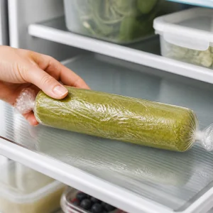 Wrapped matcha dough log chilling on a refrigerator shelf