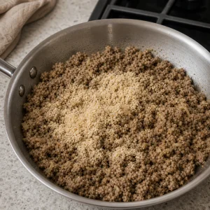 Breadcrumbs added to the cooked meat filling in a skillet