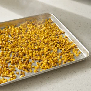 Charred corn cooling on a rimmed baking sheet