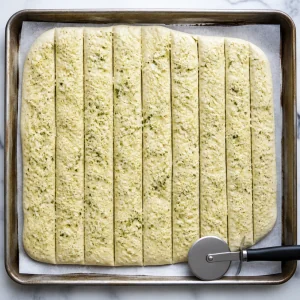 Pâte garnie de fromage coupée en longues bandes avec une roulette à pizza