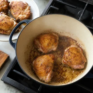 Trozos de pollo dorados por tandas en una olla de hierro