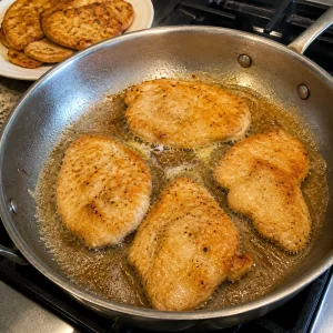 Chicken cutlets searing in butter and olive oil