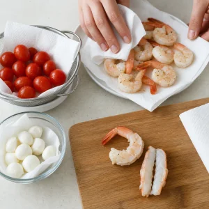 Tomaten, Mozzarella und Garnelen werden fuer Spiesse getrocknet und vorbereitet