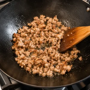 Ground pork browning in oil in a wok