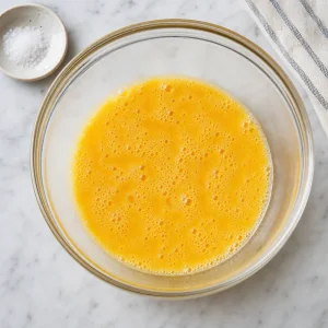 Beaten eggs with salt in a mixing bowl