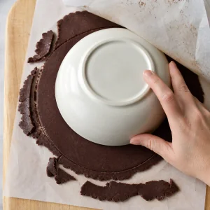 Fester Schokowaffelteig wird mit einer Schüssel rund zugeschnitten