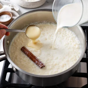 Leite, leite condensado e pau de canela adicionados ao arroz na panela.