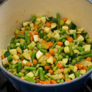 Cubos de curgete e feijao-verde misturados na base de legumes do minestrone