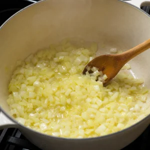 Zwiebeln werden in Olivenöl in einem großen Topf für Gemüsesuppe angedünstet