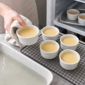Baked vanilla custards cooling on a rack before chilling.