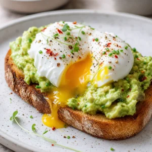 Runny poached egg yolk mixing with avocado toast