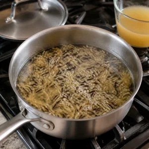 Wild rice simmering in chicken broth in a saucepan