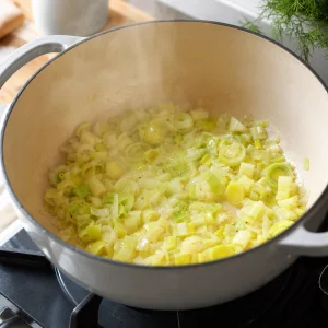 Cebolla y puerros ablandándose con mantequilla y aceite de oliva en una olla grande