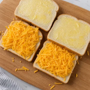 Cheddar cheese layered between buttered bread slices for sandwiches.