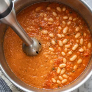 Tomaten-Bohnensuppe wird mit dem Stabmixer teilweise püriert