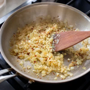 Gehackter Knoblauch und Chiliflocken werden unter weiche Zwiebeln gerührt, ohne zu bräunen.