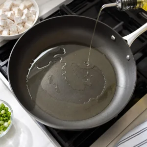 Vegetable oil shimmering in a large non-stick skillet ready for tofu.