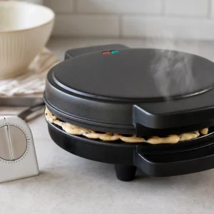 Closed waffle iron steaming while a mochi waffle cooks inside.