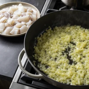 Chopped onion softening in olive oil with cuttlefish ready nearby