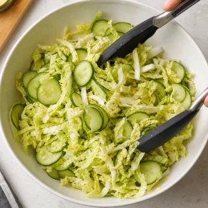 Shredded Napa cabbage and sliced cucumber tossed in a salad bowl