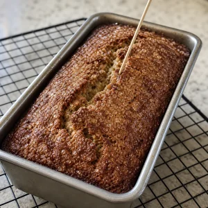 Baked banana bread checked with a wooden skewer