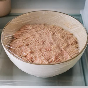 Abgedeckte Schüssel mit Frikadeller-Masse im Kühlschrank