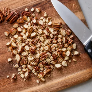 Roughly chopped toasted almonds and pecans on a cutting board