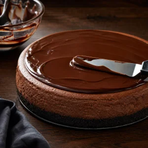 Glossy chocolate ganache spread over the chilled cheesecake